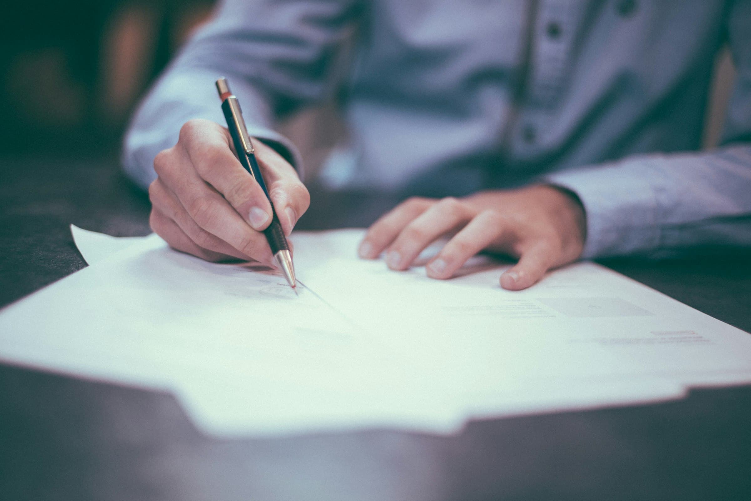 A person signing property documents at a desk