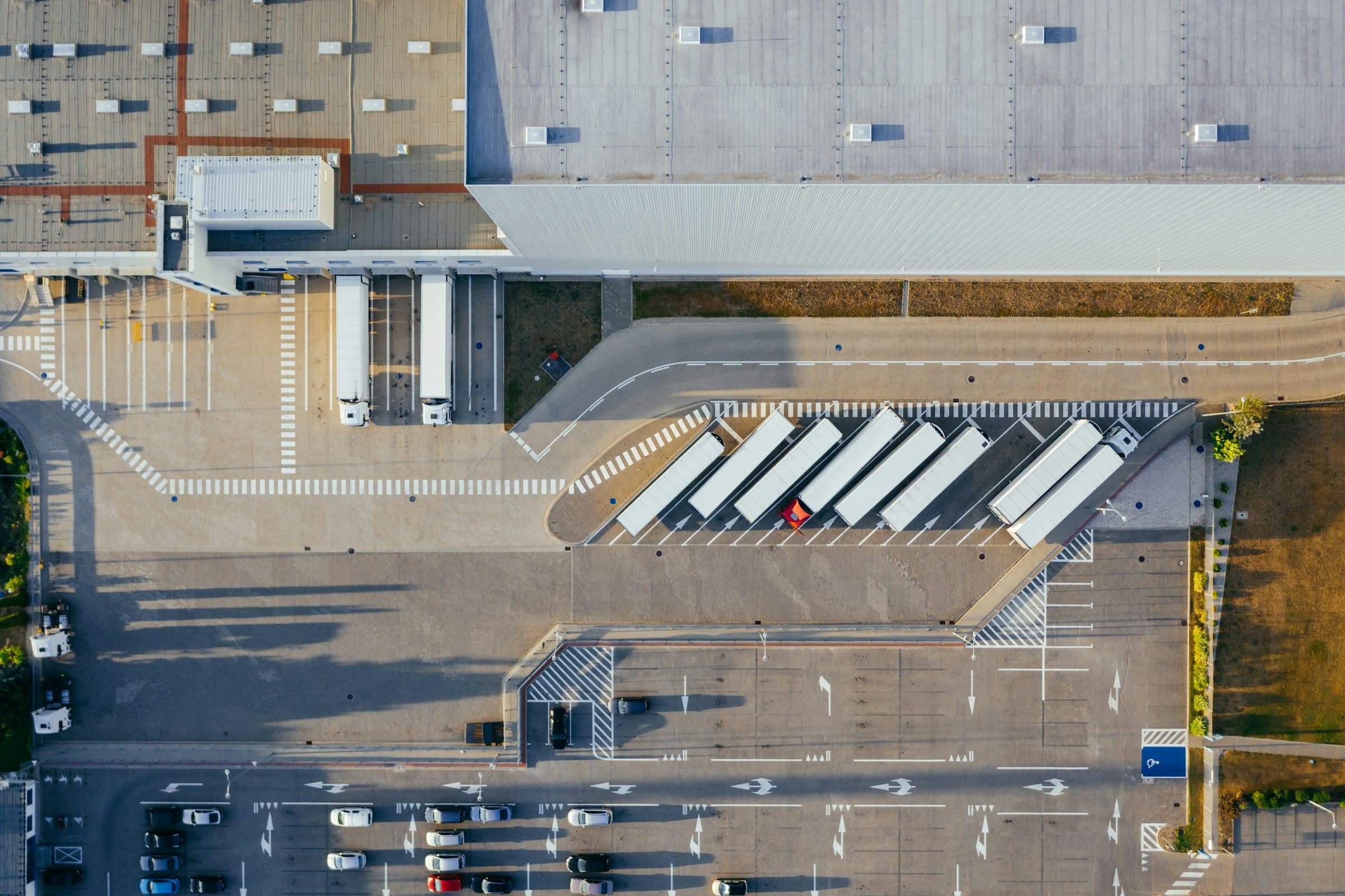 Aerial view of a logistics yard with trailers docked at a warehouse