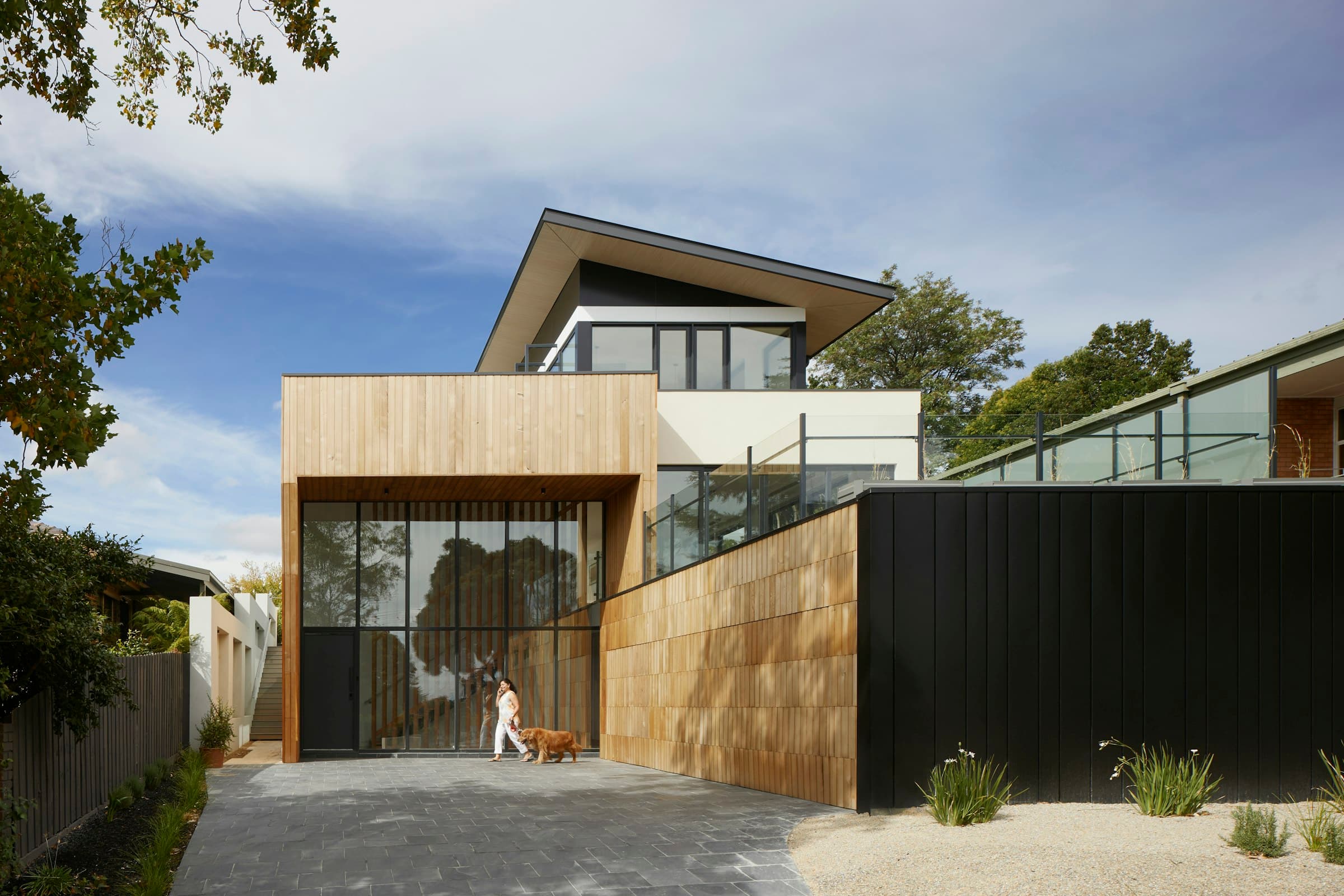 A modern timber and concrete residence with a paved driveway