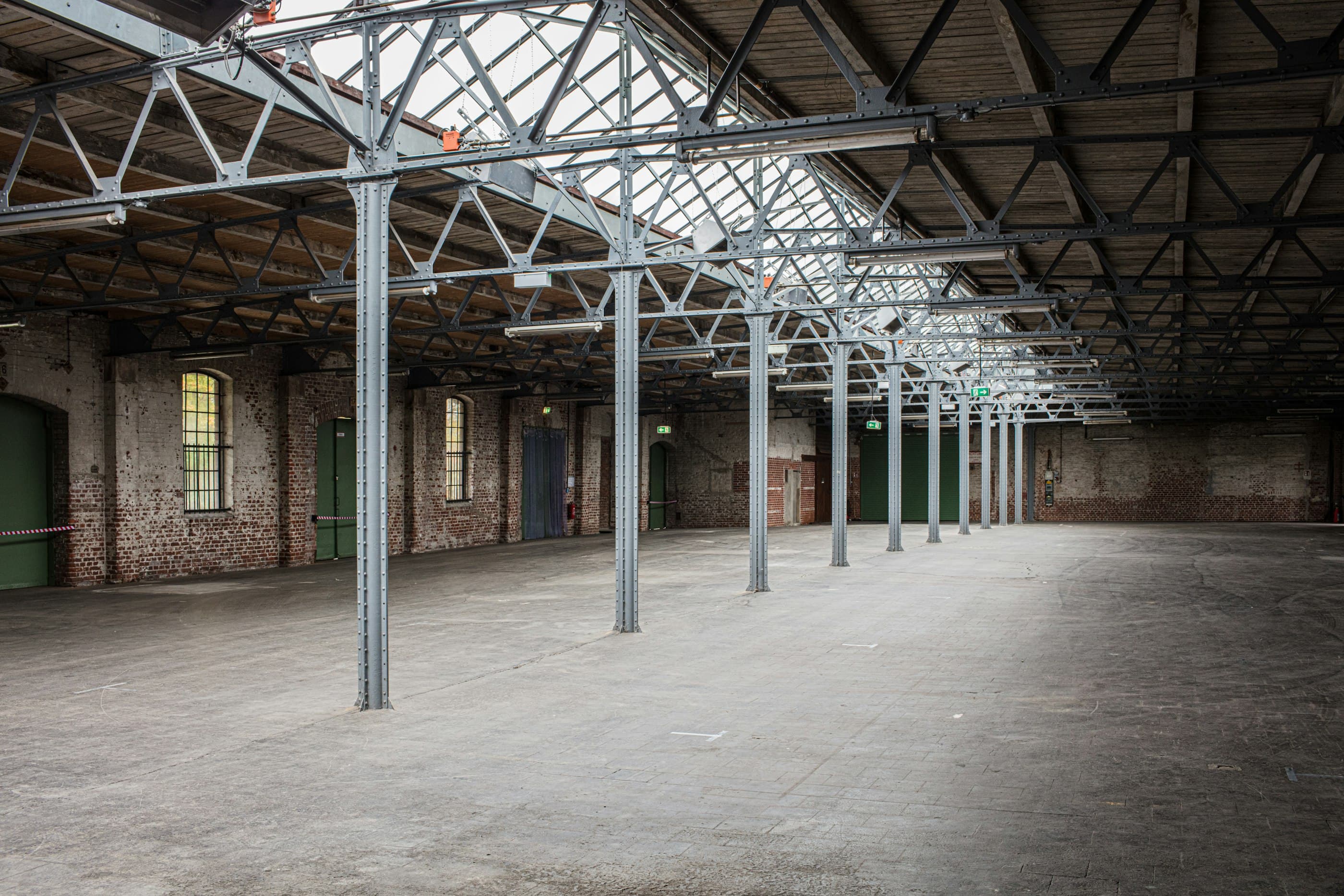 An empty industrial shed with steel roof trusses and a long skylight